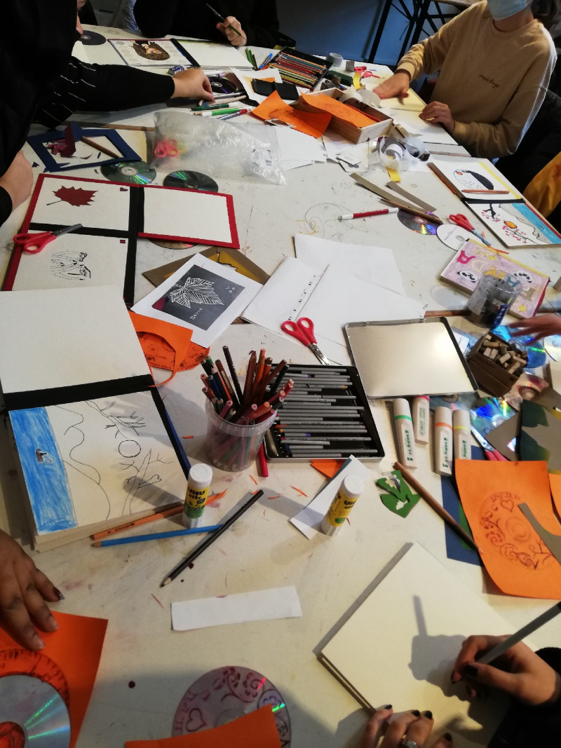 Kreatives Chaos auf einem großen Tisch, bunte Papier, Scheren Stifte, Druckvorlagen liegen kreuz und quer übereinander