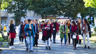 Eine große Gruppe von Menschen geht lachend auf einem breiten Fußgängerweg vorwärts.