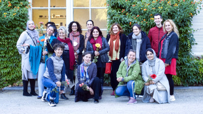 Eine Gruppe von Frauen steht vor einem Gebäude mit Bewuchs von wildem Wein.