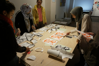 Frauen stehen um einen Tisch und schauen sich Drucke von Zeichnungen an