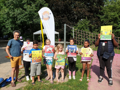 Ein Erwachsener und 7 Kinder stehen in einer Reihe und halten bunte Plakate hoch
