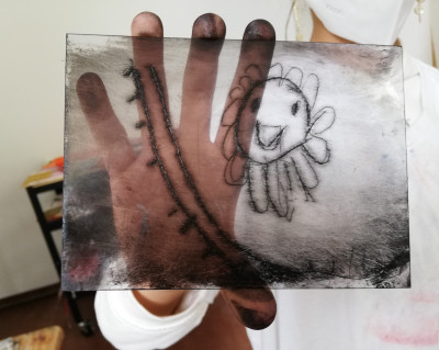 Druckstock Radierung wird von einer Hand gehalten, darauf zu sehen Sonne mit Linien