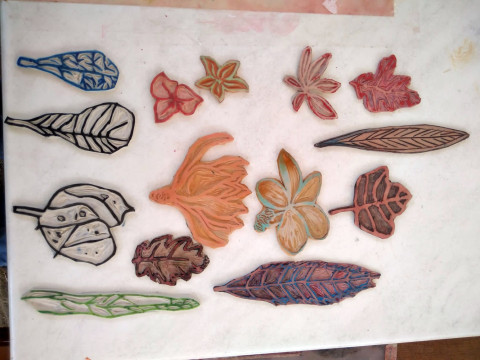 Bunte Stempel von verschiedenen Blättern, geschnitzt aus Gummi liegen auf einem weißen Blatt